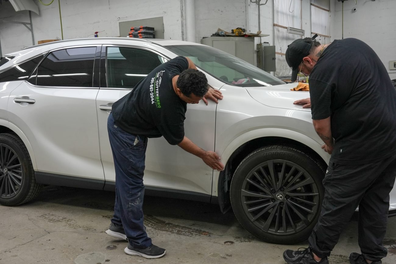 Technician working a dent out of a car panel at Guttenberg Auto Body