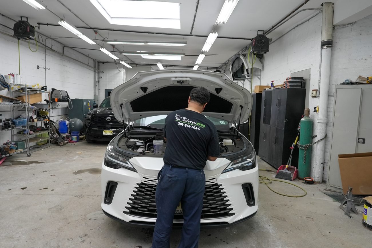 Mechanic checking the engine bay of a car at Guttenberg Auto Body
