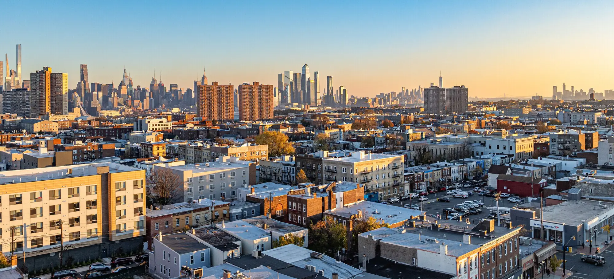 Union City, New Jersey rooftops and storefronts at sunset, with the Manhattan skyline beyond